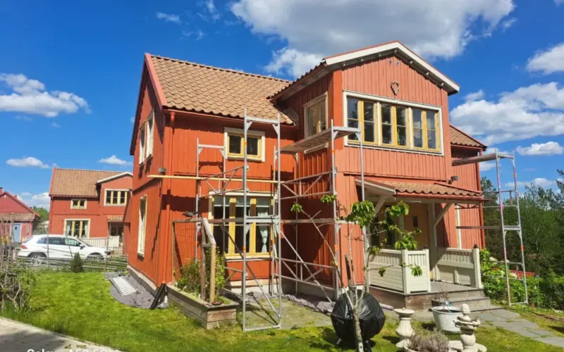 Trähus med byggställning vid fasadarbete