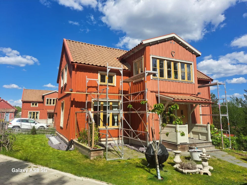 Trähus med byggställning vid fasadarbete